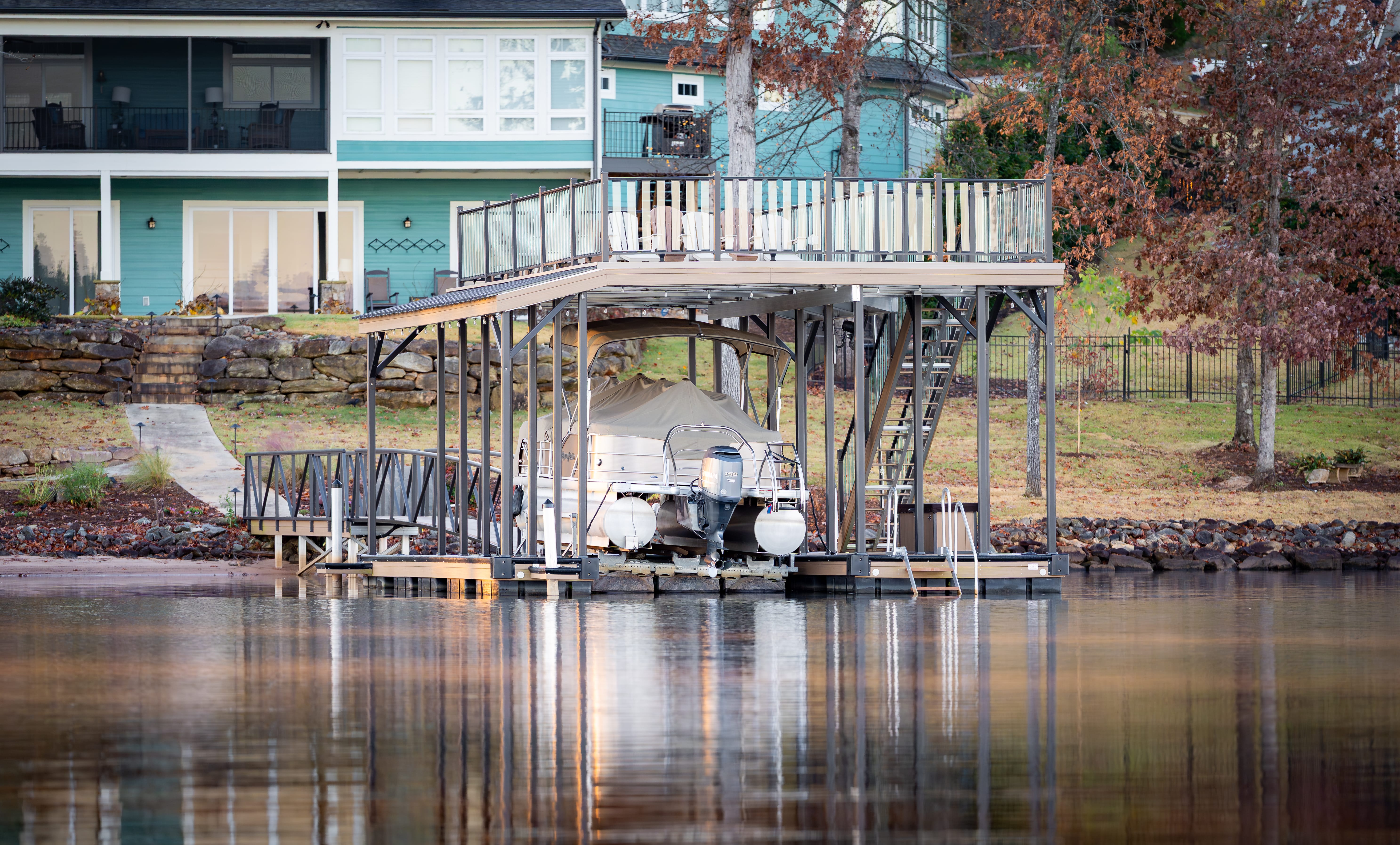 A floating boat dock on a lake behind a blue house on Georgia Lake